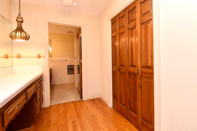 corridor with light wood-type flooring and tile walls