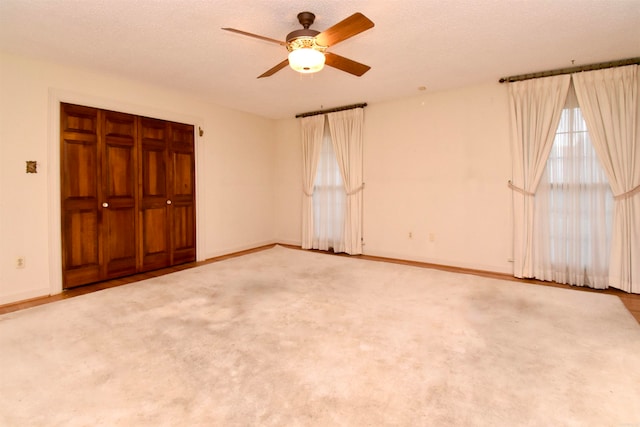 unfurnished bedroom featuring a textured ceiling, light carpet, ceiling fan, and a closet