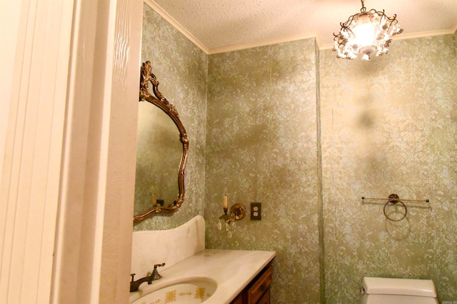 bathroom with toilet, a chandelier, a textured ceiling, ornamental molding, and vanity