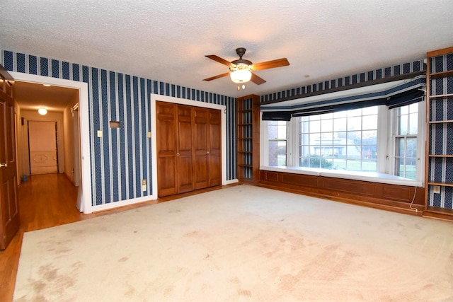 unfurnished bedroom featuring hardwood / wood-style flooring, ceiling fan, a textured ceiling, and a closet