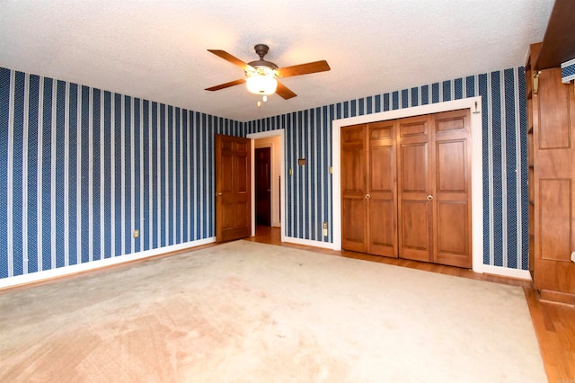 unfurnished bedroom featuring light carpet, a textured ceiling, ceiling fan, and a closet