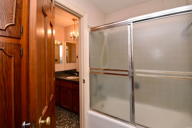 bathroom featuring a notable chandelier, shower / bath combination with glass door, a textured ceiling, and vanity