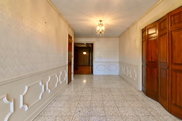 corridor with an inviting chandelier, ornamental molding, and a textured ceiling