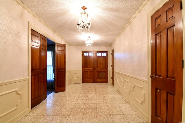 doorway with a healthy amount of sunlight, an inviting chandelier, crown molding, and a textured ceiling