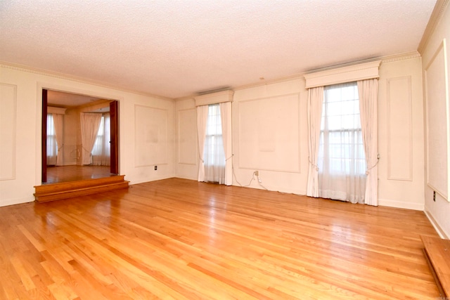 unfurnished living room with light wood-type flooring, a wealth of natural light, and a textured ceiling