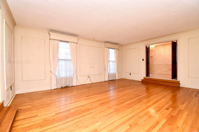 spare room with light hardwood / wood-style floors, a textured ceiling, and crown molding