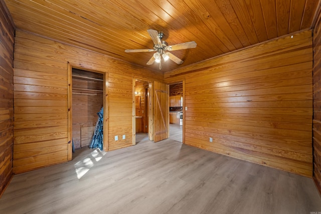 unfurnished bedroom with wooden ceiling, ceiling fan, wooden walls, and light hardwood / wood-style flooring