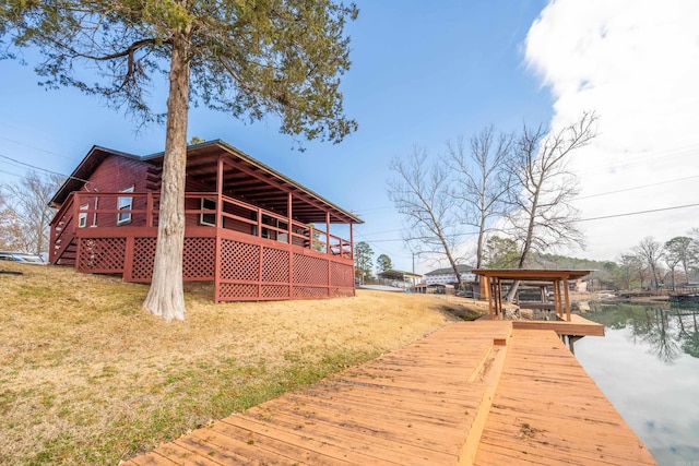 exterior space featuring a deck with water view and a lawn