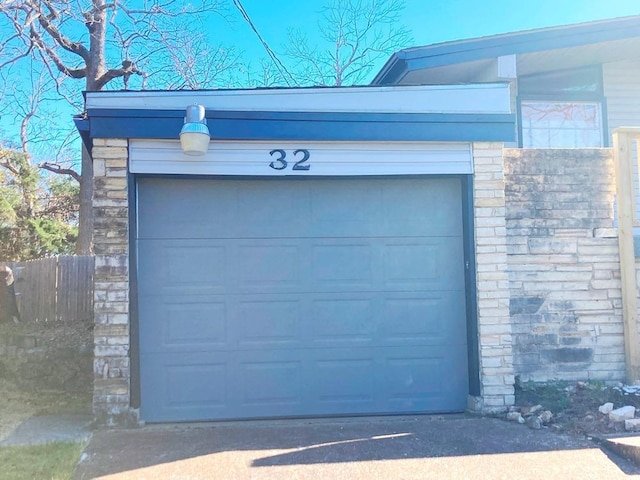 garage featuring fence and driveway