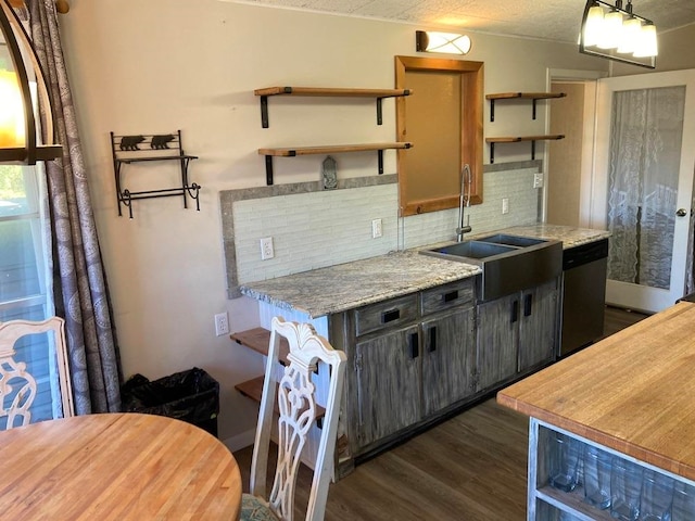 kitchen with tasteful backsplash, dark hardwood / wood-style floors, light stone countertops, sink, and stainless steel dishwasher