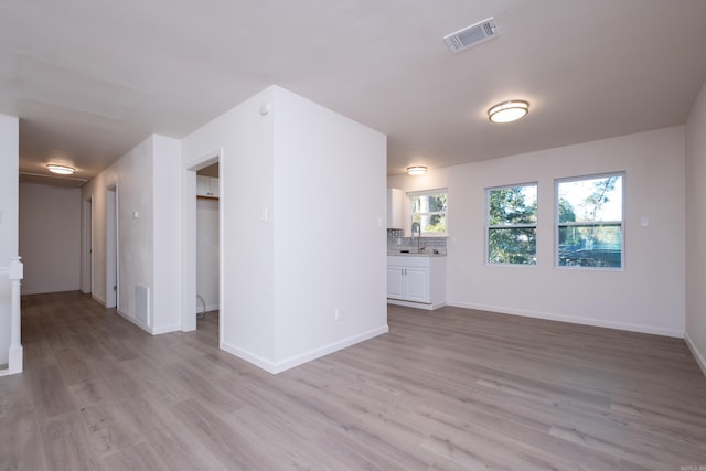 unfurnished living room with sink and light wood-type flooring