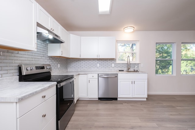 kitchen featuring light hardwood / wood-style floors, white cabinetry, sink, appliances with stainless steel finishes, and backsplash