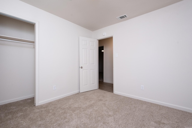 unfurnished bedroom featuring light carpet and a closet