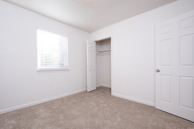 unfurnished bedroom with light colored carpet and a closet