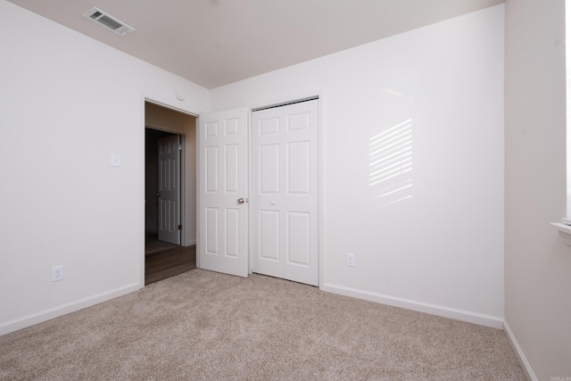 unfurnished bedroom featuring light colored carpet and a closet