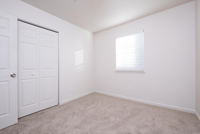 unfurnished bedroom with a closet and light colored carpet