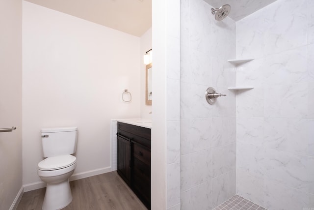 bathroom featuring hardwood / wood-style floors, vanity, toilet, and a tile shower