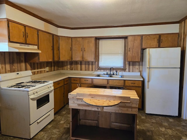 kitchen featuring a textured ceiling, wooden walls, sink, and white appliances