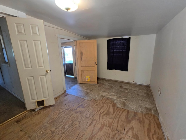 empty room featuring hardwood / wood-style floors and vaulted ceiling