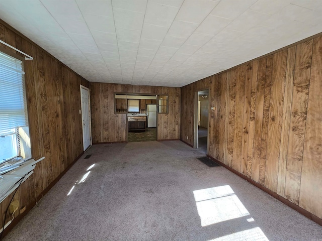 carpeted spare room featuring wood walls