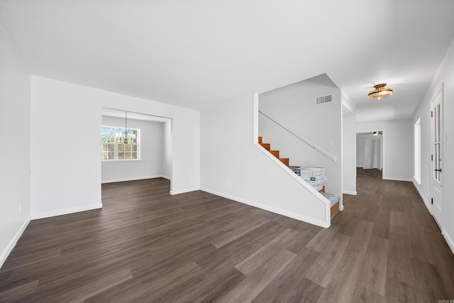 unfurnished living room with dark wood-type flooring and a chandelier