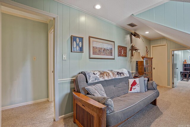 living room with vaulted ceiling, light colored carpet, ornamental molding, and a textured ceiling