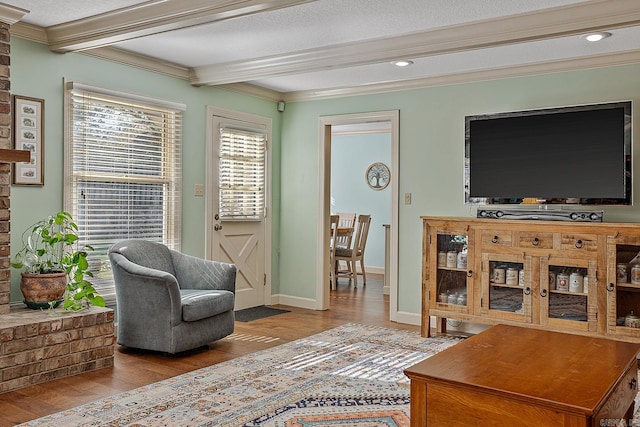 sitting room with ornamental molding, light hardwood / wood-style floors, a textured ceiling, and beam ceiling