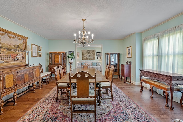 dining space with hardwood / wood-style flooring, a chandelier, a textured ceiling, and crown molding