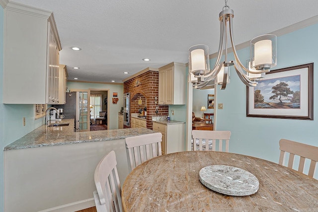 dining room featuring an inviting chandelier, hardwood / wood-style floors, a textured ceiling, sink, and crown molding