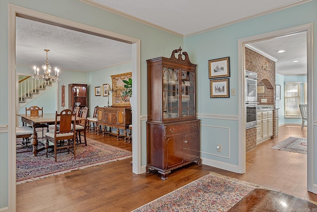 dining space featuring hardwood / wood-style floors, a textured ceiling, an inviting chandelier, and crown molding