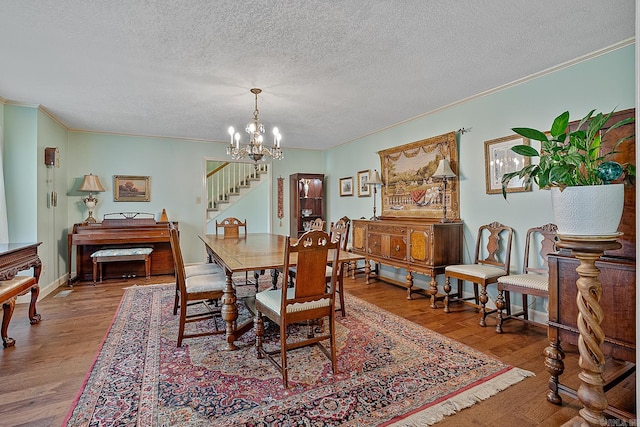 dining area with an inviting chandelier, hardwood / wood-style flooring, crown molding, and a textured ceiling