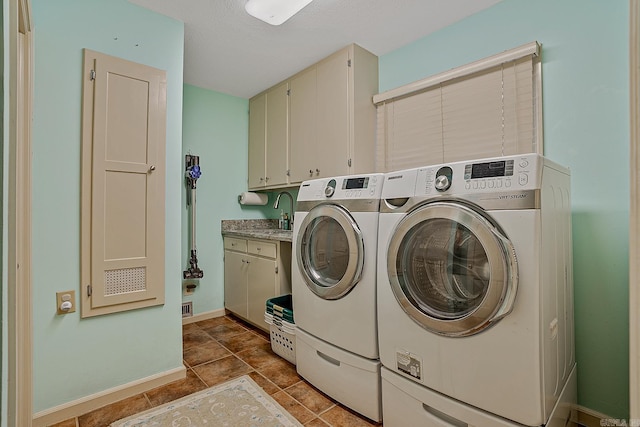 laundry area with cabinets, a textured ceiling, light tile patterned floors, sink, and washing machine and clothes dryer