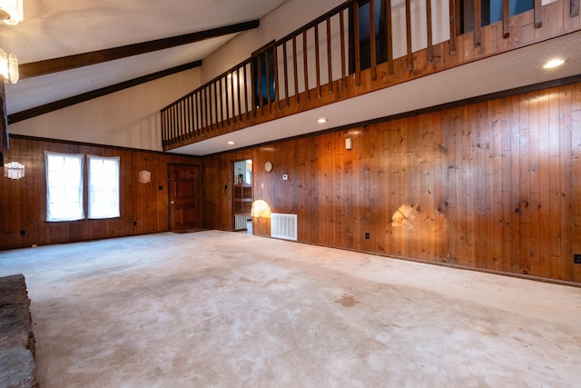 unfurnished living room featuring high vaulted ceiling, beamed ceiling, and carpet flooring