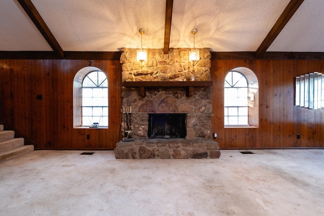 unfurnished living room with plenty of natural light, wood walls, and beam ceiling