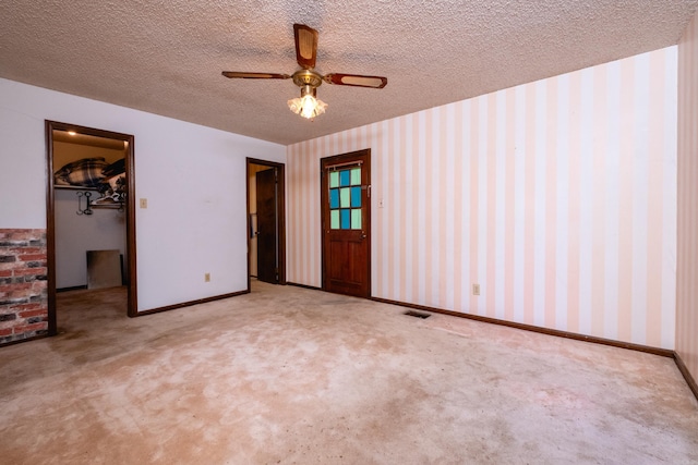 unfurnished bedroom featuring light carpet, ceiling fan, a textured ceiling, a walk in closet, and a closet