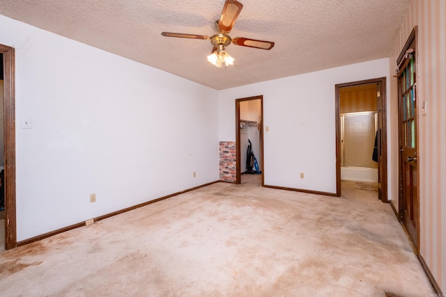 unfurnished bedroom with a closet, a spacious closet, a textured ceiling, light colored carpet, and ceiling fan