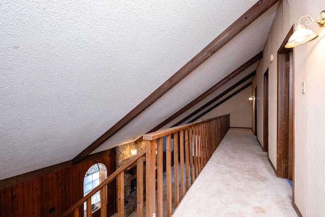 hall featuring wood walls, a textured ceiling, and vaulted ceiling