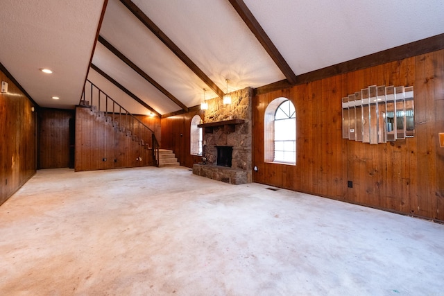 unfurnished living room featuring a fireplace, wood walls, vaulted ceiling with beams, and carpet floors