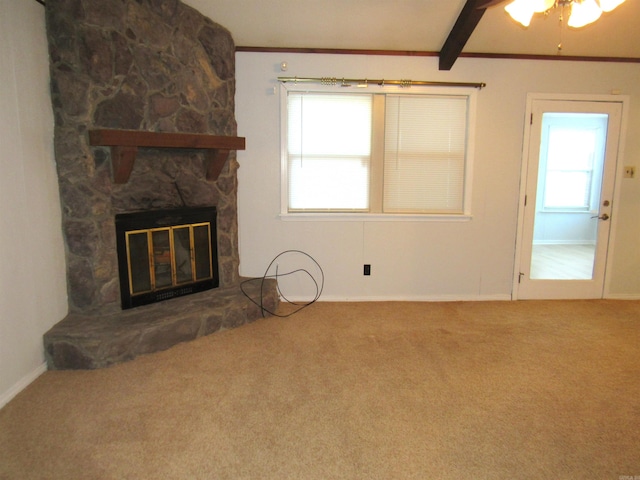 unfurnished living room with a stone fireplace, beamed ceiling, a wealth of natural light, and carpet