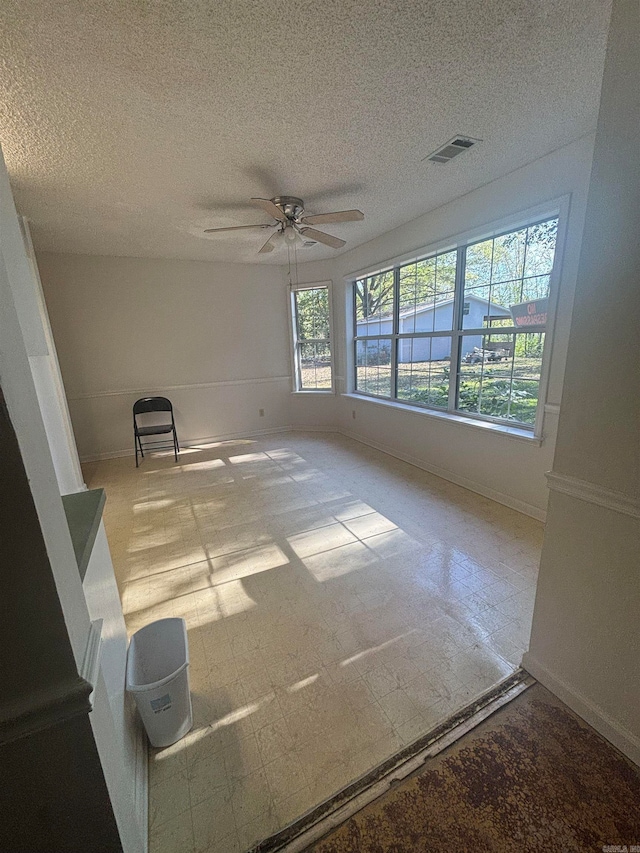 empty room with a textured ceiling and ceiling fan