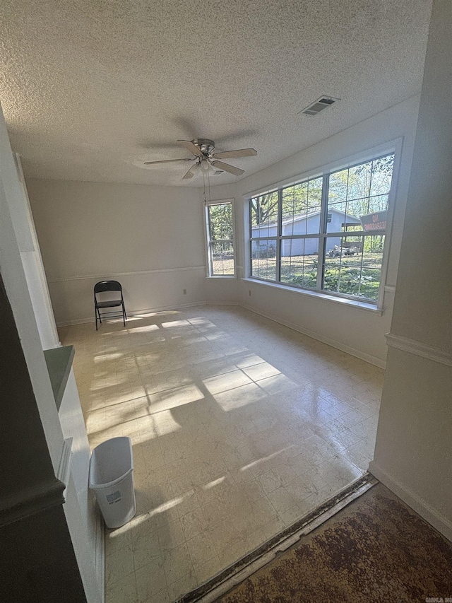spare room with a ceiling fan, baseboards, and a textured ceiling