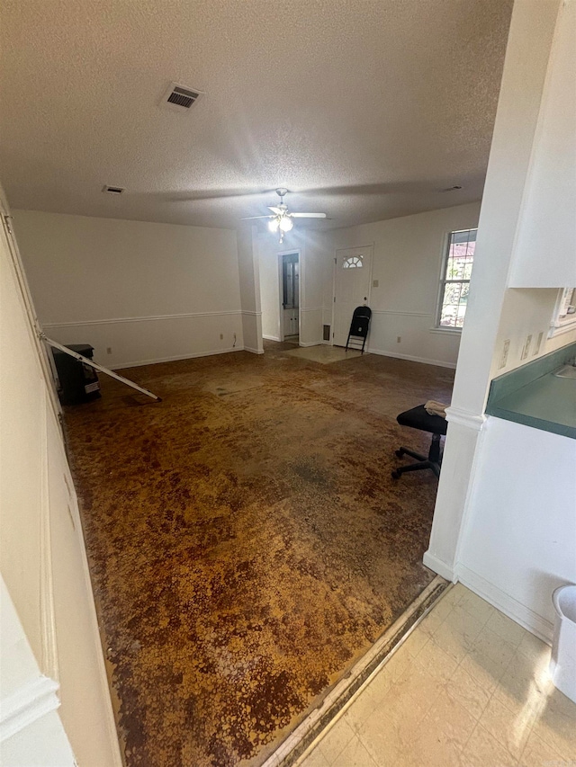 interior space with ceiling fan and a textured ceiling