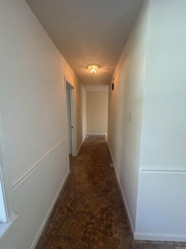 corridor featuring a textured ceiling and carpet flooring