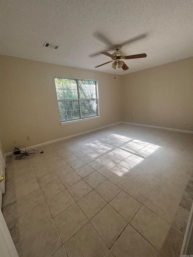 spare room with ceiling fan, a textured ceiling, and light tile patterned floors