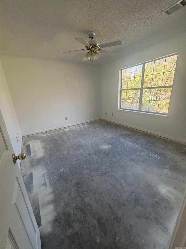 unfurnished room with concrete floors, ceiling fan, a textured ceiling, and baseboards