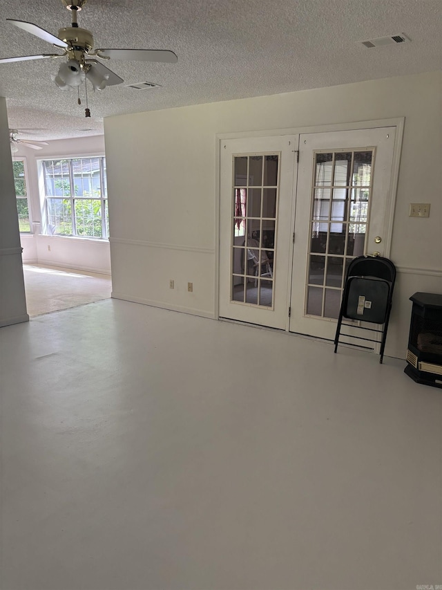 unfurnished living room with a ceiling fan, a textured ceiling, concrete floors, and heating unit