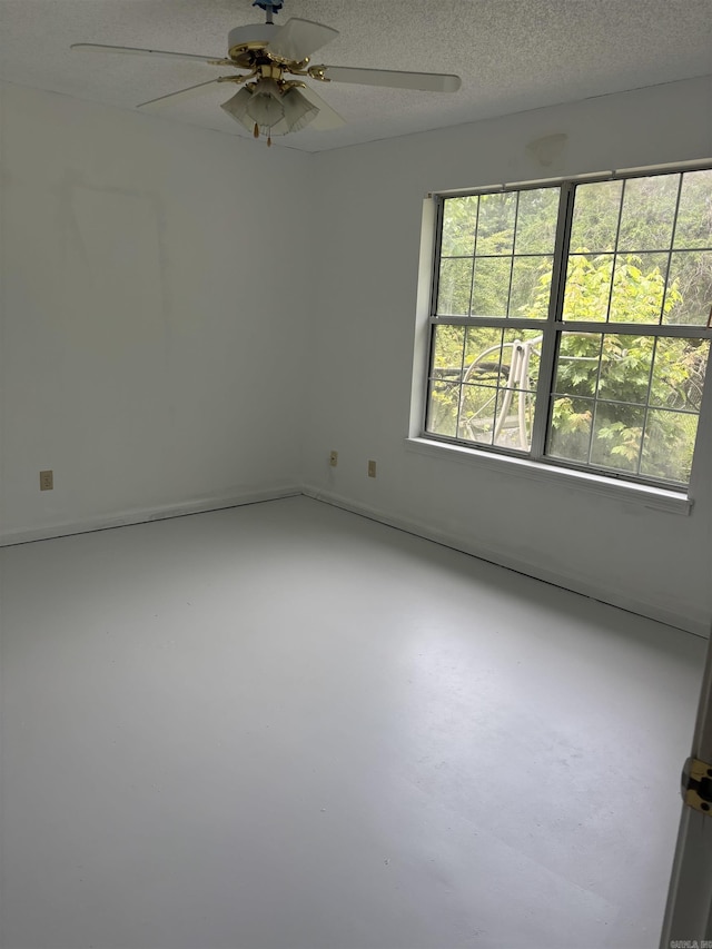 spare room with concrete flooring, ceiling fan, and a textured ceiling