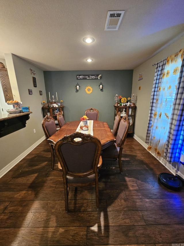 dining area with a textured ceiling and dark hardwood / wood-style flooring