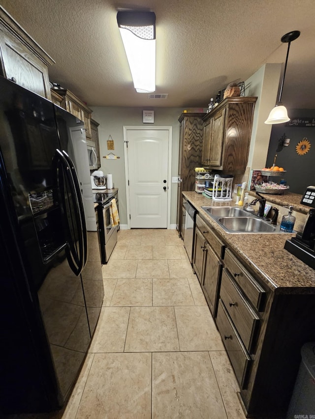 kitchen featuring light tile patterned flooring, stainless steel appliances, a textured ceiling, pendant lighting, and sink