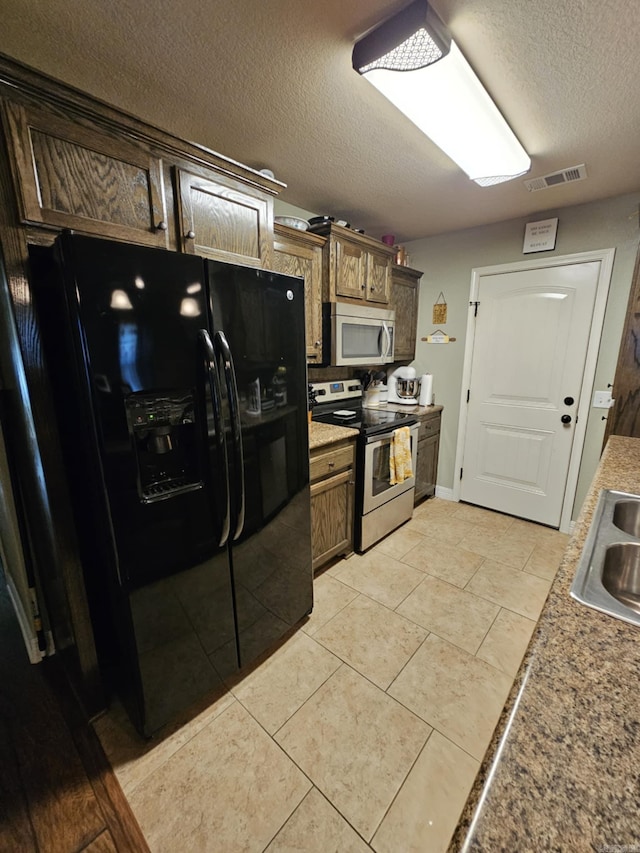 kitchen featuring stainless steel appliances, a textured ceiling, sink, and light tile patterned floors